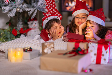 Happy children play with soft fake snow by a window during a festive Christmas morning celebration indoors at home together.