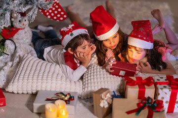 Happy children play with soft fake snow by a window during a festive Christmas morning celebration indoors at home together.
