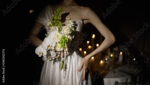 Quadro su tela Bride holding white orchid bouquet with greenery at candlelit reception