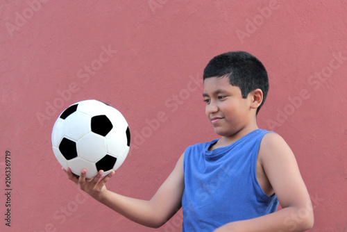 12-year-old Latino boy with dark skin plays with his soccer ball to practice for the game 