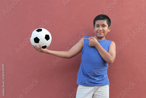 12-year-old Latino boy with dark skin plays with his soccer ball to practice for the game 