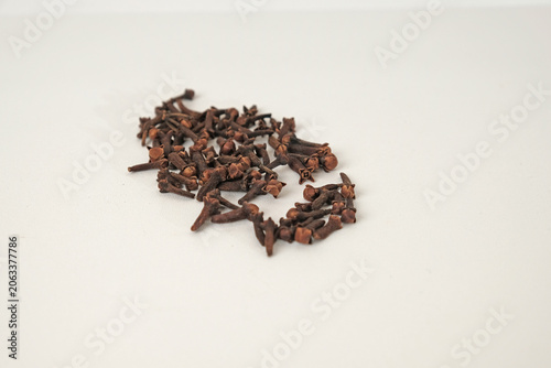 Cloves scattered on pure white background. Each clove has a textured, rich brown surface. Natural aroma suggests spice, warmth, and flavor. Ideal for culinary, medicinal