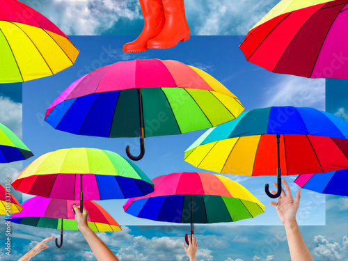 Brightly colored umbrellas fill the scene, each segment in vivid hues. A pair of red boots and hands reaching for the umbrellas add a quirky touch to the composition.
