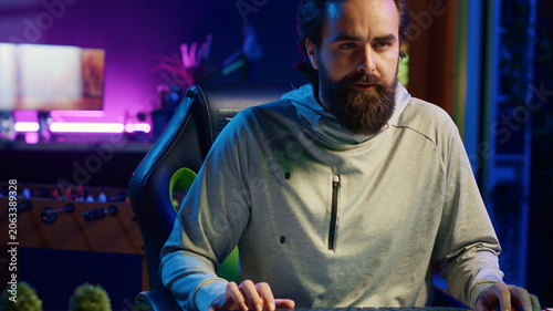 Tableau sur toile Man arriving home from work, unwinding by playing videogames in neon lit apartment, gamer starting gaming session, trying to relax by competing in multiplayer tournaments