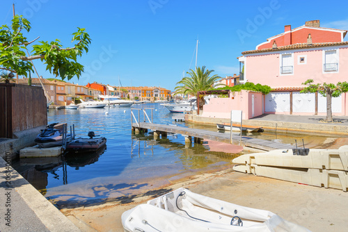 A boat launch a wooden dock surrounded by pastel colored luxury  homes at the waterfront community of Port Grimaud, France, near Saint-Tropez along the French Riviera, Mediterranean Sea.