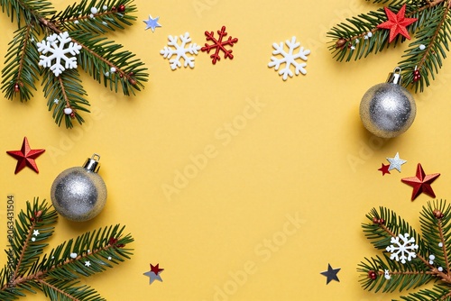 A yellow background with christmas decorations and fir branches