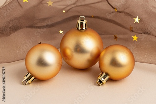 Three gold christmas ornaments sitting on top of a brown ribbon