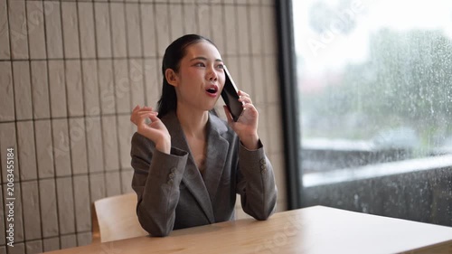 Businesswoman talking on phone while sitting at table near window