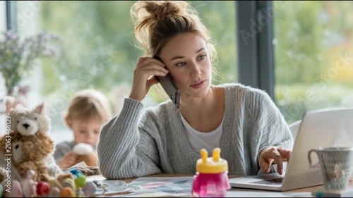 Working mother talking on the phone while her child plays in the background at home concept of busy mom working remotely