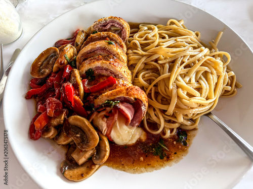 Golden-browned chicken cordon bleu sliced to reveal melted cheese and ham, served with buttery linguine, sautéed mushrooms, and roasted red peppers in a rich savory sauce.