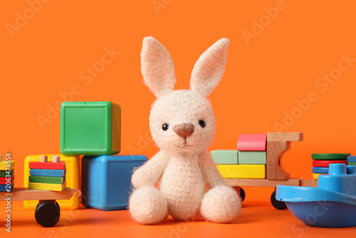 Obraz na plátne Adorable white knitted bunny toy with colorful wooden and plastic blocks on brig