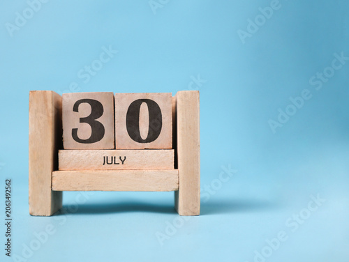 Quadro su tela A wooden block calendar for July thirtieth on a light blue background