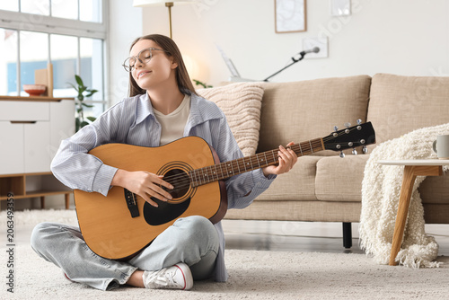 Young girl playing guitar at home