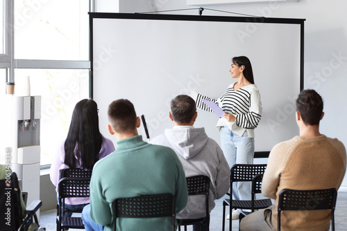 Female business speaker with hearing aid conducting seminar to people in office