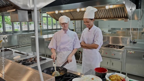 Senior Female Chef Instructor Teach Junior Student Cooking With Frying Pan