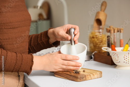Woman grinding peppercorns ...