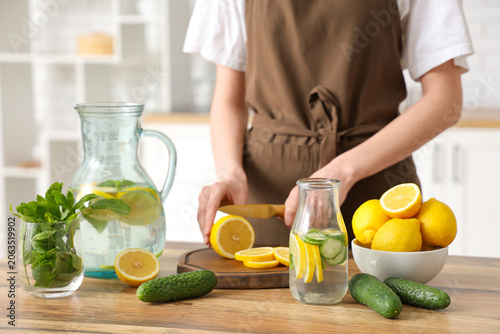 Young woman cutting lemon f...