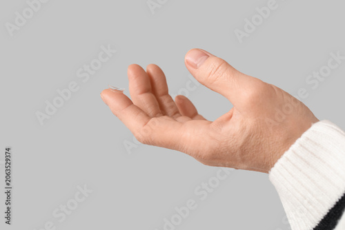 Canvastavla Female hand with contact lens on grey background