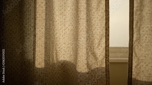 Sunlight streaming through sheer patterned curtains in a cozy living room setting.