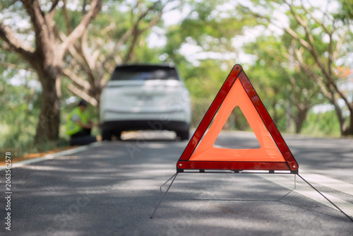 Fotografía Car breaks down on a quiet road and a person inspects the vehicle with a warning