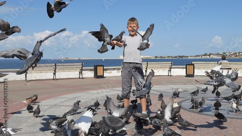 A child surrounded by pigeons. Boys feed birds. The delight of children from communicating with wildlife.