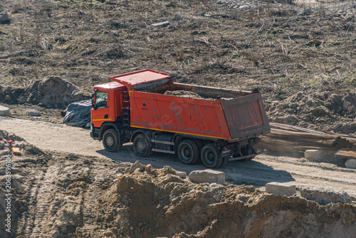 Construction Site with Red Dump Truck Unloading Materials