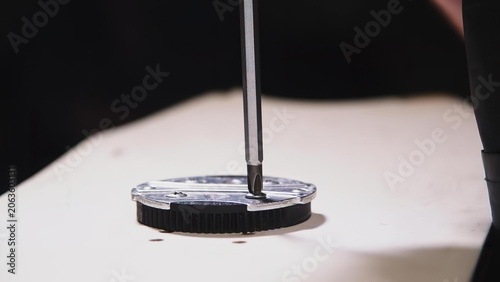 Close-up of a watchmaker assembling a watch on a white table