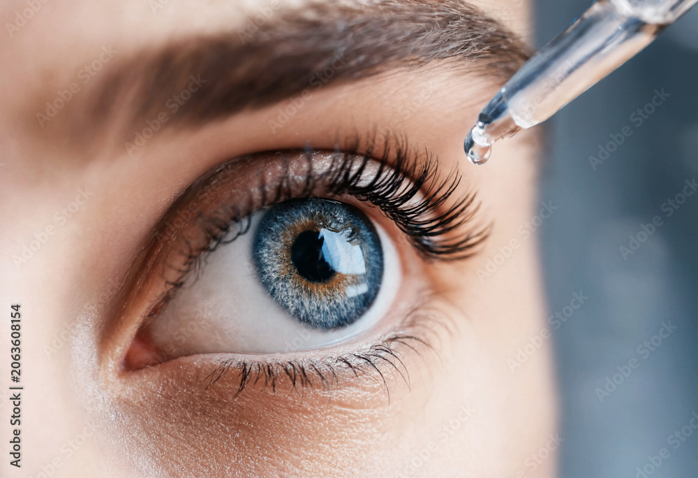 Naklejka premium Close up blue eye with dropper applying liquid drop iris pupil