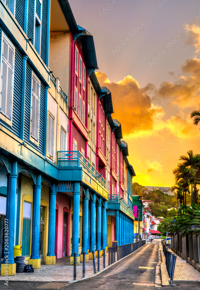 Naklejka premium Vibrant row of multi-colored buildings and traditional shutters at sunset along a street in Fort-de-France, Martinique, Caribbean France
