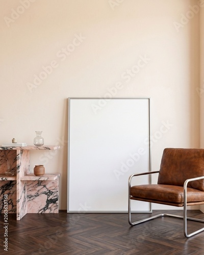 Blank silver frame mockup leaning on wall with pink marble console and leather chair