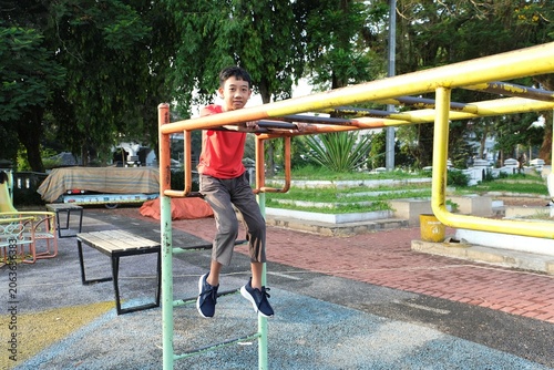 Young boy exercising on playground bars outdoors during active childhood recreation and healthy lifestyle activity.