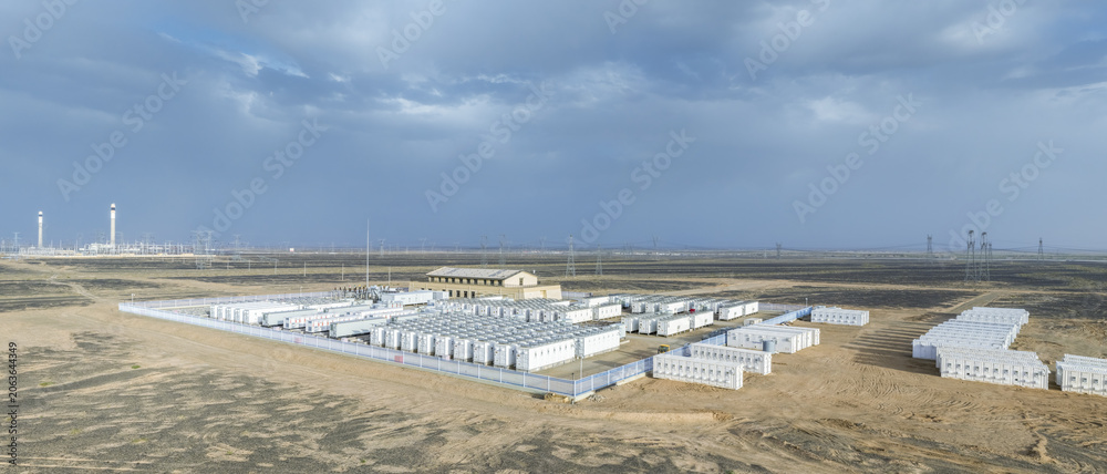 Obraz premium Large-Scale Battery Energy Storage Plant Under Construction in Gobi Desert with Adjacent Molten Salt Solar Thermal Power Station