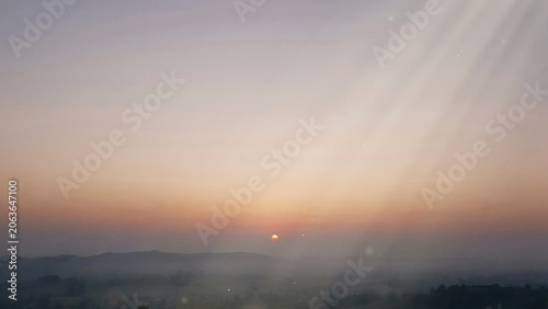 Sunset over a hazy mountain range with sun rays in the sky
