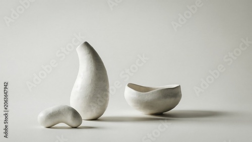 Three white ceramic sculptures on a light gray background with shadows