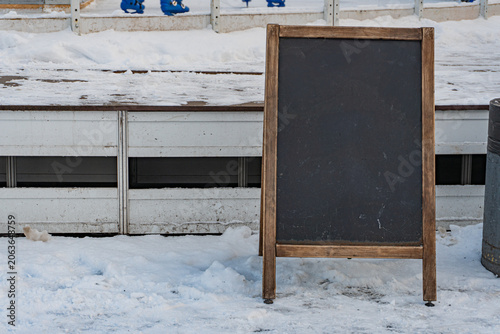 A blackboard standing on a wooden frame, potentially outdoors amidst snowy surroundings The board is clean and uncluttered with no visible texts or objects