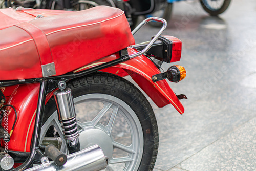 Fotografia Vintage red motorcycle with chrome detailing, angled on a tiled floor, two rear-