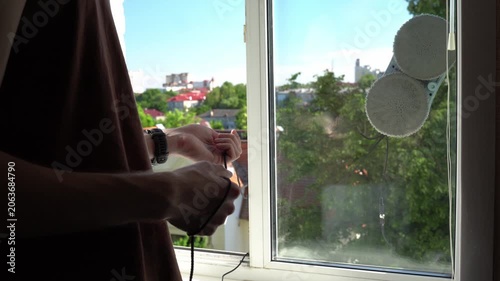 The young man's hands are insured with the help of a robot windshield cleaning cable, which is engaged in cleaning the outer glass on the window