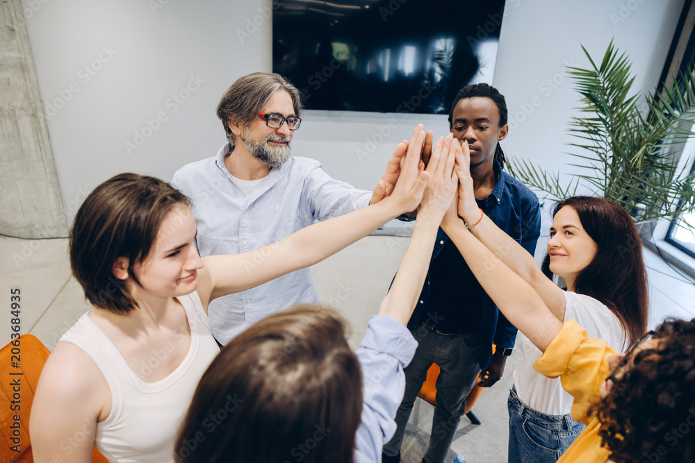 Obraz premium Diverse business team showing unity with high five in modern office
