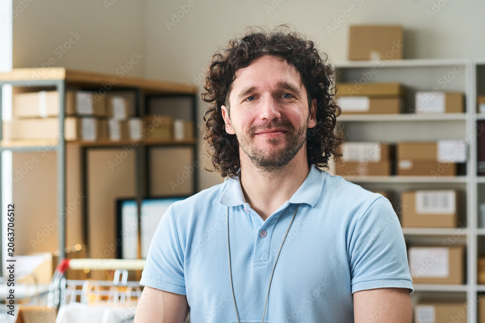 Fototapeta premium Portrait of young man managing order pickup point in delivery workspace, representing retail logistics and fulfillment. For ecommerce, courier service, small business marketing