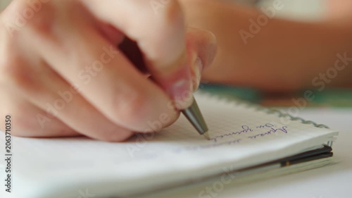 Close up shot of a hand writing text with a pen in a notebook. Macro shot of a student doing homework. University student studying and writing notes for an exam. Education concept.
