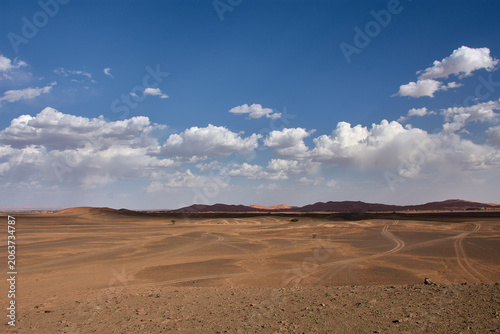 фотографія A dirt and gravel track leads towards the fine sand hills of the Merzouga Desert in Morocco