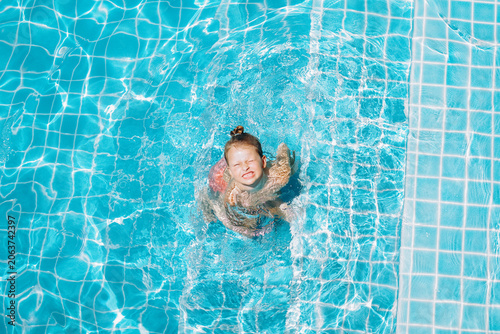 little cute girl in swimming pool. Child smiling. Top view portrait 