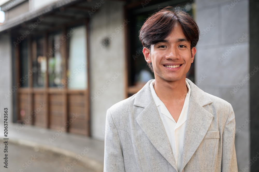 Obraz premium Portrait of smiling non-binary Thai Isan professional on street
