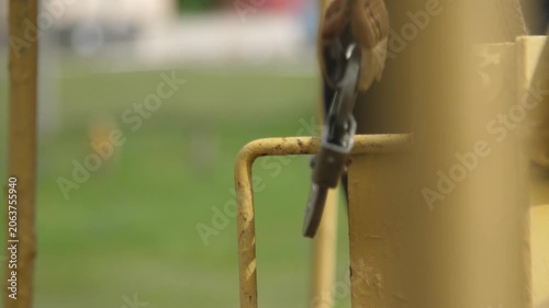 Worker man hand attaching metal carabiner with cable to metal construction.