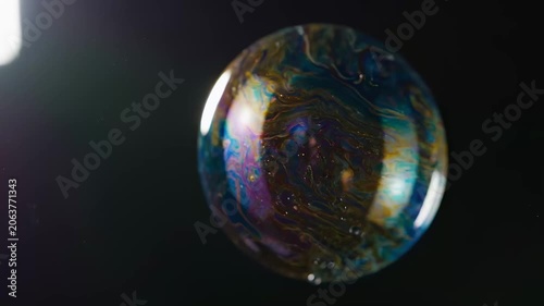 Iridescent Bubble Reflecting Colorful Swirls and Light on a Dark Background