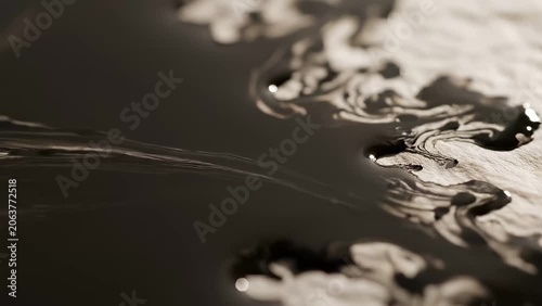 Abstract black ink swirling and dissolving on a light-colored surface, creating organic patterns and textures