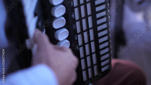 Man musician masterfully playing accordion on blurred background close-up hand.