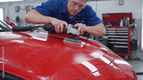 Expertly Polishing a Car's Surface: A Detailed Look at the Technique and Equipment Used to Achieve a Flawless Finish on a Red Vehicle in a Professional Workshop