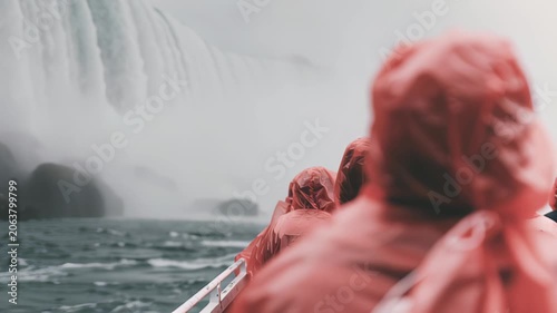 Adventurers in red ponchos experience majestic waterfall from boat