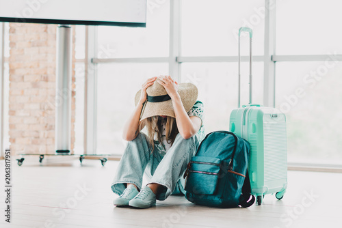 Photography Young woman sitting at an airport terminal with travel luggage and feeling distr